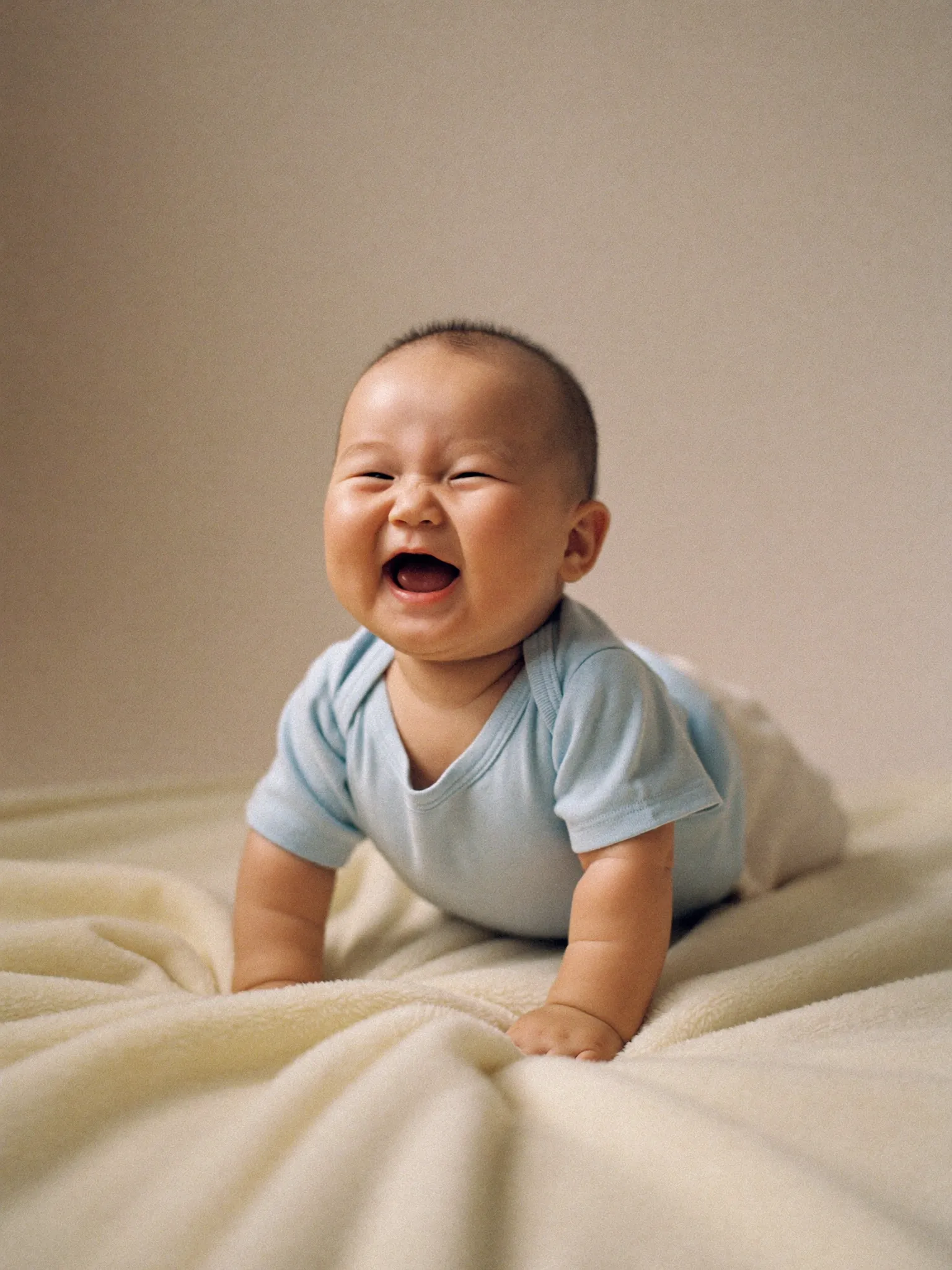 크림색 담요 위에서 활짝 웃는 100일 아기